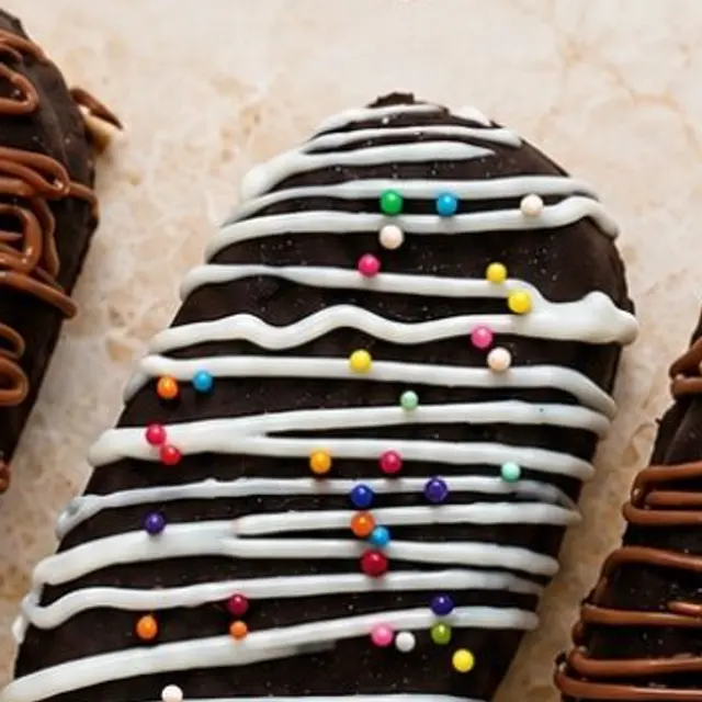 A chocolate-coated cakesicle drizzled with white chocolate and sprinkles