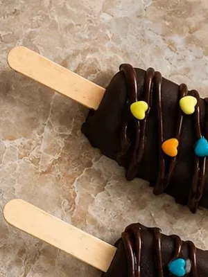 A chocolate-coated brownie popsicle on a wooden stick