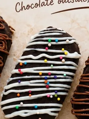 A chocolate-coated cakesicle with sprinkles on a wooden stick