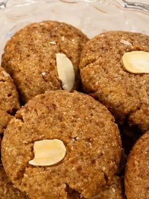 Almond and oats cookies on a glass plate, topped with almond slices